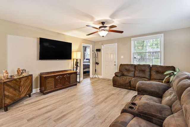 living area with light wood-type flooring, ceiling fan, and baseboards