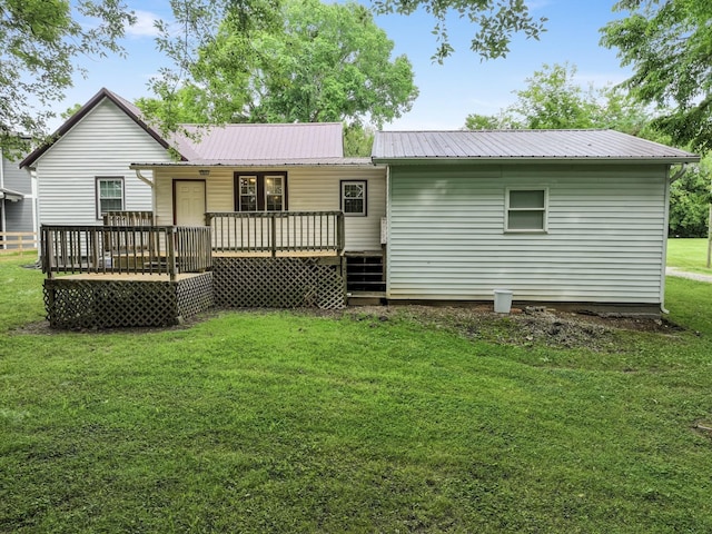 rear view of property featuring metal roof, a deck, and a lawn