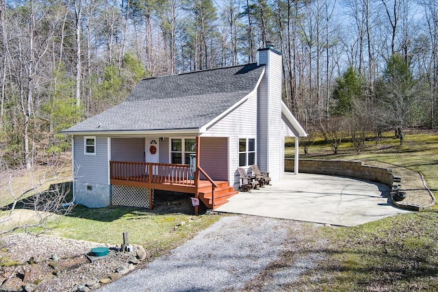 view of front of house featuring a front yard, roof with shingles, crawl space, a chimney, and a patio area