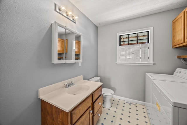 bathroom with washing machine and clothes dryer, toilet, vanity, a textured ceiling, and baseboards