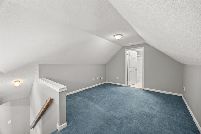 bonus room featuring dark carpet, vaulted ceiling, a textured ceiling, and baseboards