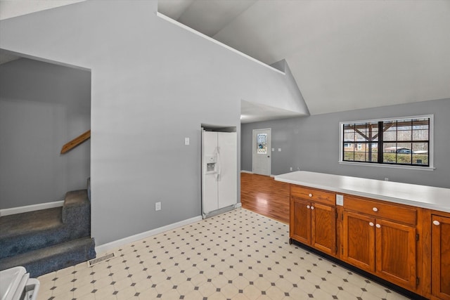 kitchen with white refrigerator with ice dispenser, brown cabinets, a wealth of natural light, light countertops, and visible vents