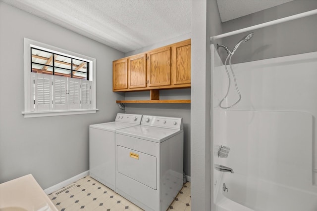 laundry area with light floors, cabinet space, a textured ceiling, washer and dryer, and baseboards