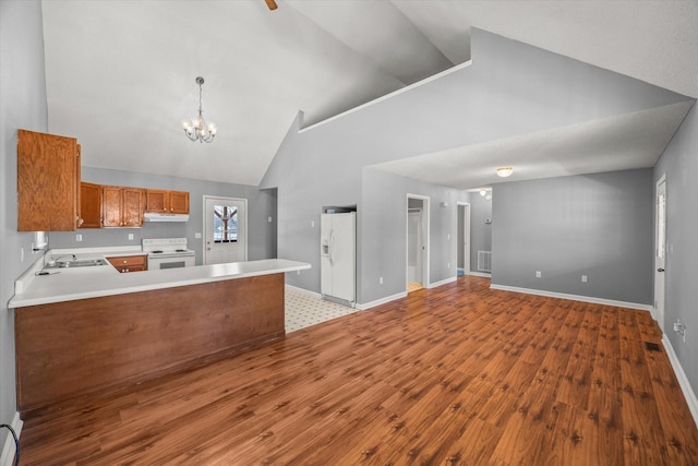 kitchen with pendant lighting, light countertops, white appliances, a peninsula, and under cabinet range hood