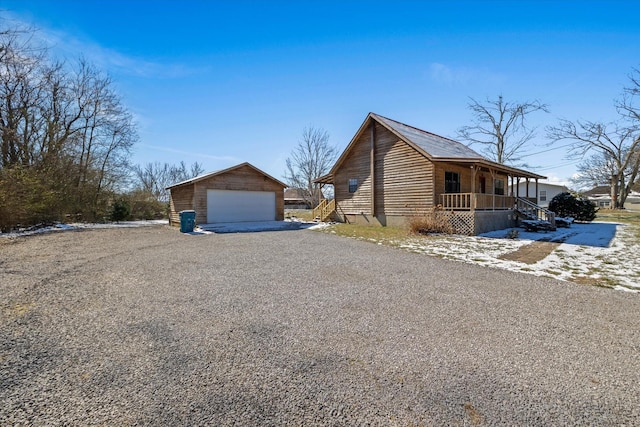 view of side of property featuring covered porch, a detached garage, and an outdoor structure