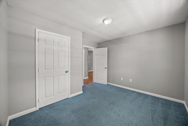 unfurnished bedroom featuring carpet flooring, a textured ceiling, and baseboards