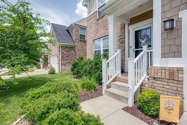 doorway to property with an attached garage, roof with shingles, a lawn, and brick siding