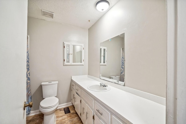 bathroom with baseboards, visible vents, toilet, a textured ceiling, and vanity