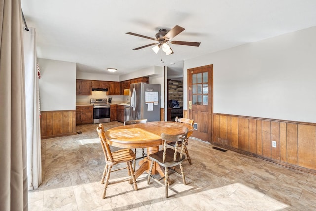 dining space with a wainscoted wall, wood walls, and visible vents