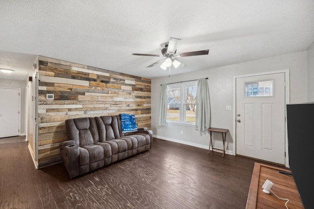 living room with dark wood-type flooring, wooden walls, and a textured ceiling