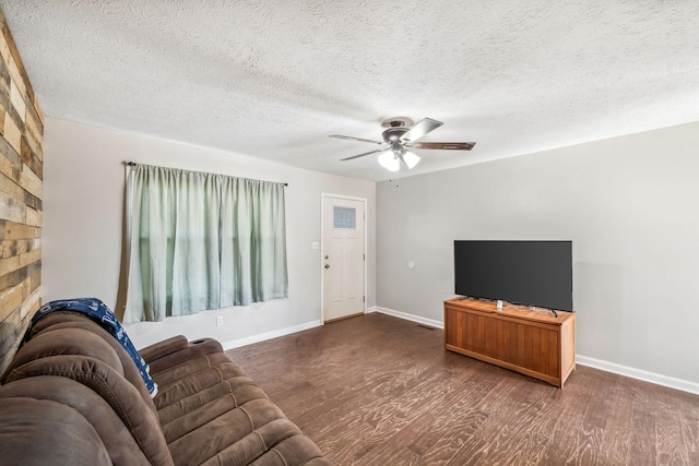 living room with a textured ceiling, wood finished floors, a ceiling fan, and baseboards