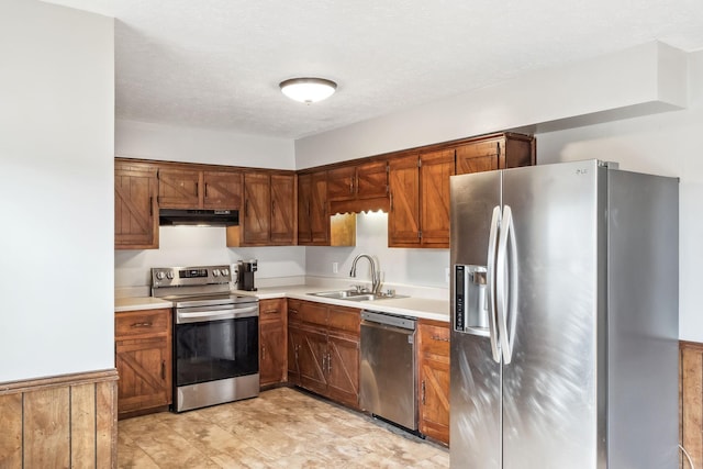 kitchen featuring stainless steel appliances, light countertops, a sink, and under cabinet range hood