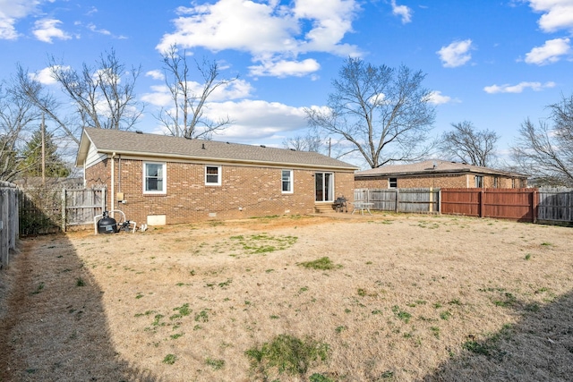 back of house with a fenced backyard and brick siding