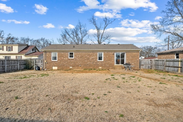 back of house featuring crawl space, a yard, a fenced backyard, and brick siding