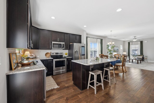 kitchen featuring appliances with stainless steel finishes, dark wood-style flooring, a kitchen island, and a kitchen breakfast bar