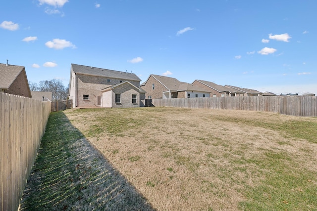 rear view of property featuring a fenced backyard, a residential view, and a lawn