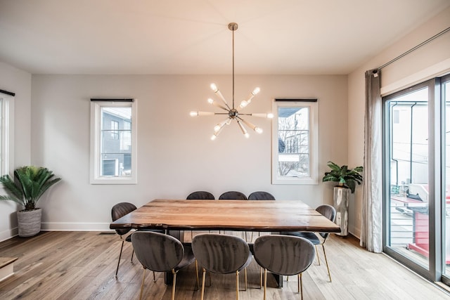 dining area with light wood-type flooring, a notable chandelier, and baseboards