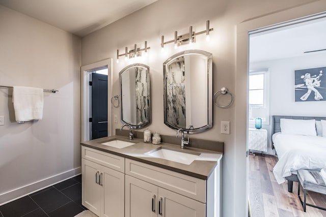 full bath featuring double vanity, a sink, baseboards, and ensuite bathroom