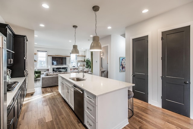 kitchen featuring open floor plan, decorative light fixtures, stainless steel appliances, white cabinetry, and a sink