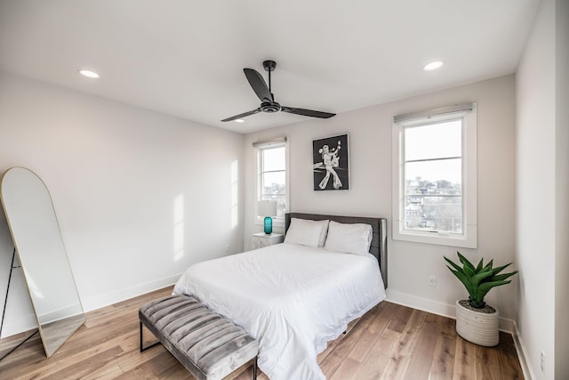 bedroom with light wood-style floors, multiple windows, and baseboards