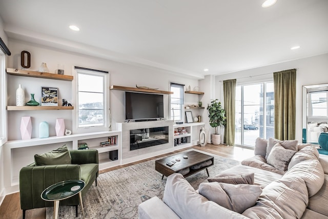 living area with a glass covered fireplace, wood finished floors, and recessed lighting