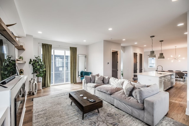 living area featuring recessed lighting, light wood-style flooring, and an inviting chandelier