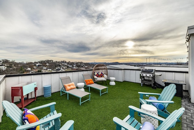 patio terrace at dusk featuring a grill and a lawn