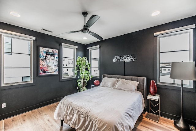 bedroom featuring light wood finished floors, ceiling fan, multiple windows, and visible vents