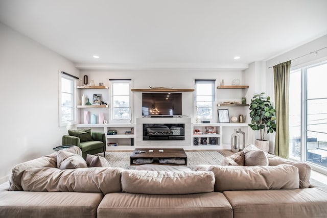 living room featuring a healthy amount of sunlight, recessed lighting, and a glass covered fireplace