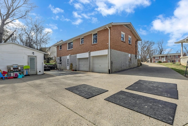 view of property exterior with a garage, a residential view, brick siding, and driveway