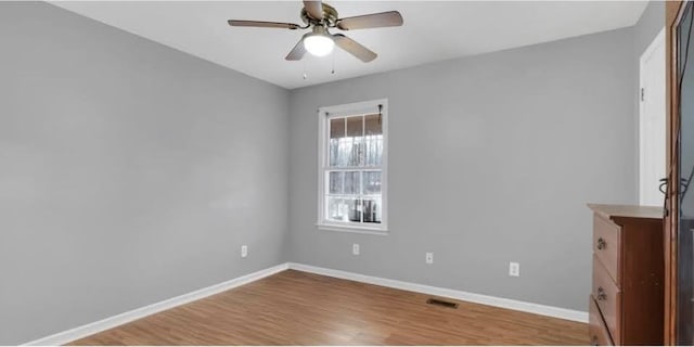 spare room with ceiling fan, light wood-type flooring, and baseboards