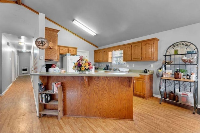 kitchen featuring lofted ceiling, light countertops, freestanding refrigerator, light wood finished floors, and brown cabinetry