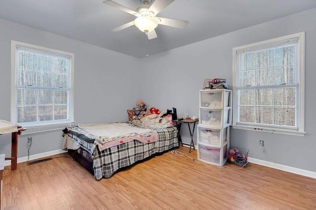 bedroom featuring multiple windows, baseboards, and wood finished floors