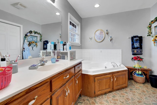full bathroom featuring a garden tub, recessed lighting, vanity, visible vents, and stone finish floor