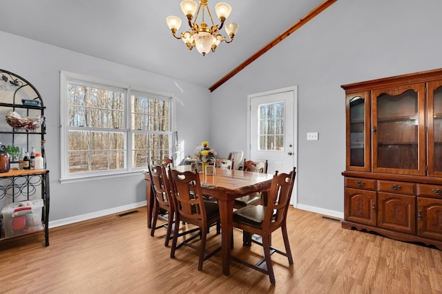 dining room featuring vaulted ceiling, an inviting chandelier, a wealth of natural light, and light wood-style floors