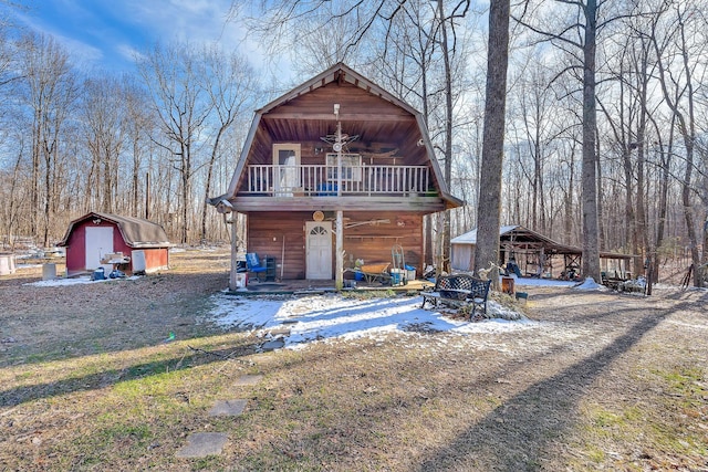 view of front of house featuring an outbuilding, a balcony, a gambrel roof, and a storage unit