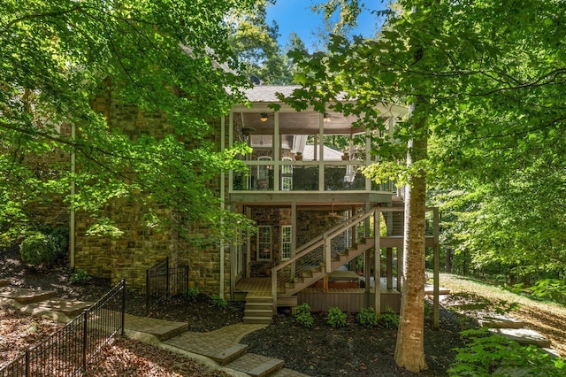 rear view of property with stone siding, stairway, fence, and a sunroom