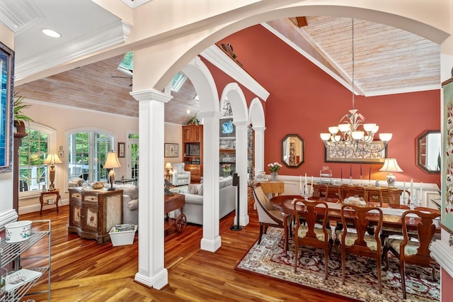 dining space featuring arched walkways, a notable chandelier, decorative columns, ornamental molding, and wood finished floors