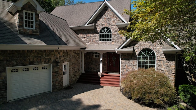 view of front facade featuring a garage, decorative driveway, and roof with shingles