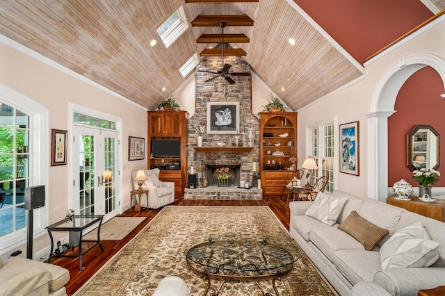 living room with high vaulted ceiling, a stone fireplace, wooden ceiling, a skylight, and wood finished floors