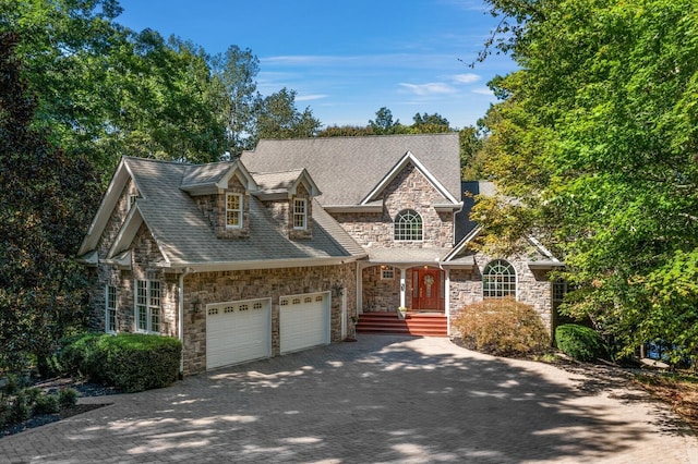 view of front of home with a garage, stone siding, a shingled roof, and decorative driveway