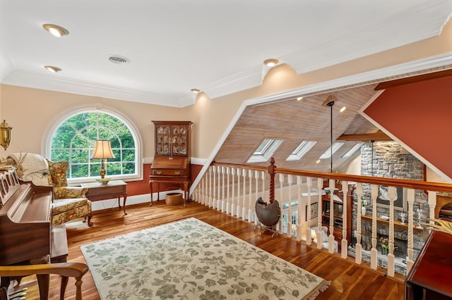 living area featuring a skylight, visible vents, ornamental molding, wood finished floors, and baseboards