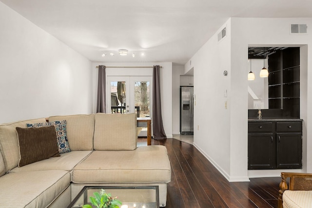 living room featuring dark wood-style floors, baseboards, and visible vents