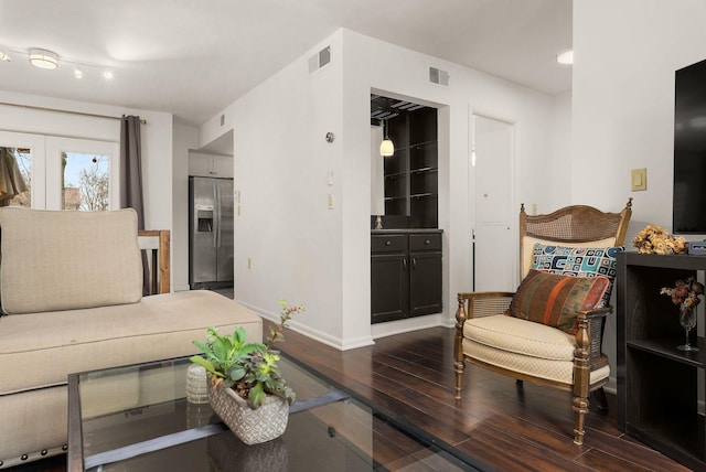 interior space featuring dark wood-style floors, visible vents, stainless steel refrigerator with ice dispenser, and baseboards