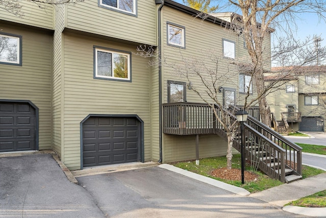 exterior space with driveway, an attached garage, and stairs