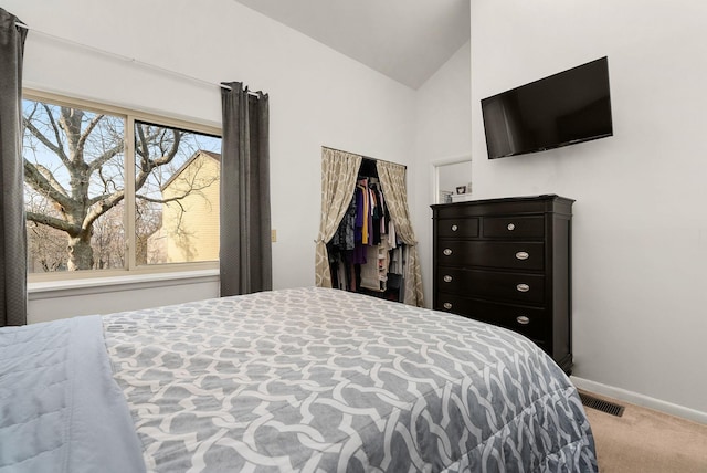 carpeted bedroom with vaulted ceiling, a closet, visible vents, and baseboards