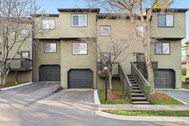 townhome / multi-family property featuring a garage, driveway, and stairs