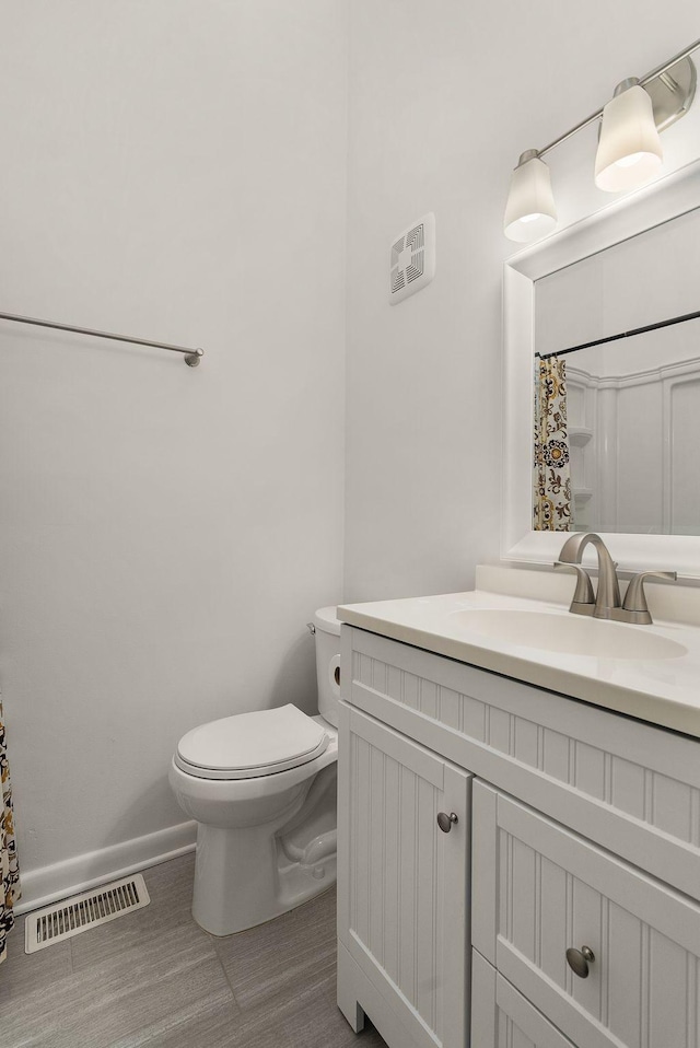 bathroom featuring visible vents, a shower with shower curtain, toilet, vanity, and baseboards