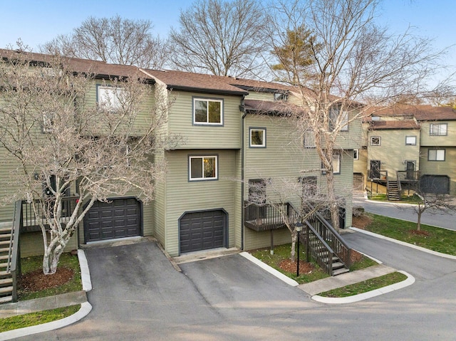 view of front of home with driveway, an attached garage, and stairway