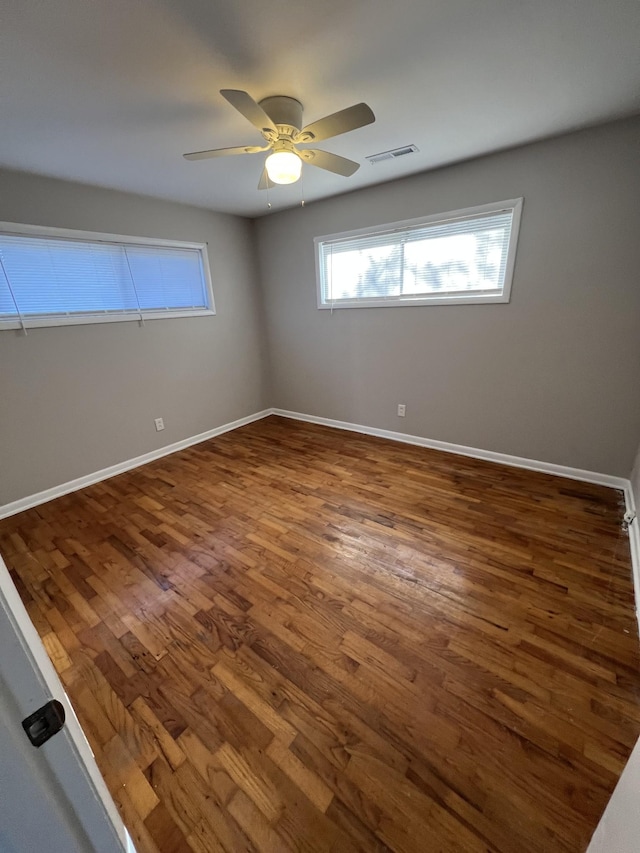 spare room with visible vents, dark wood finished floors, baseboards, and ceiling fan